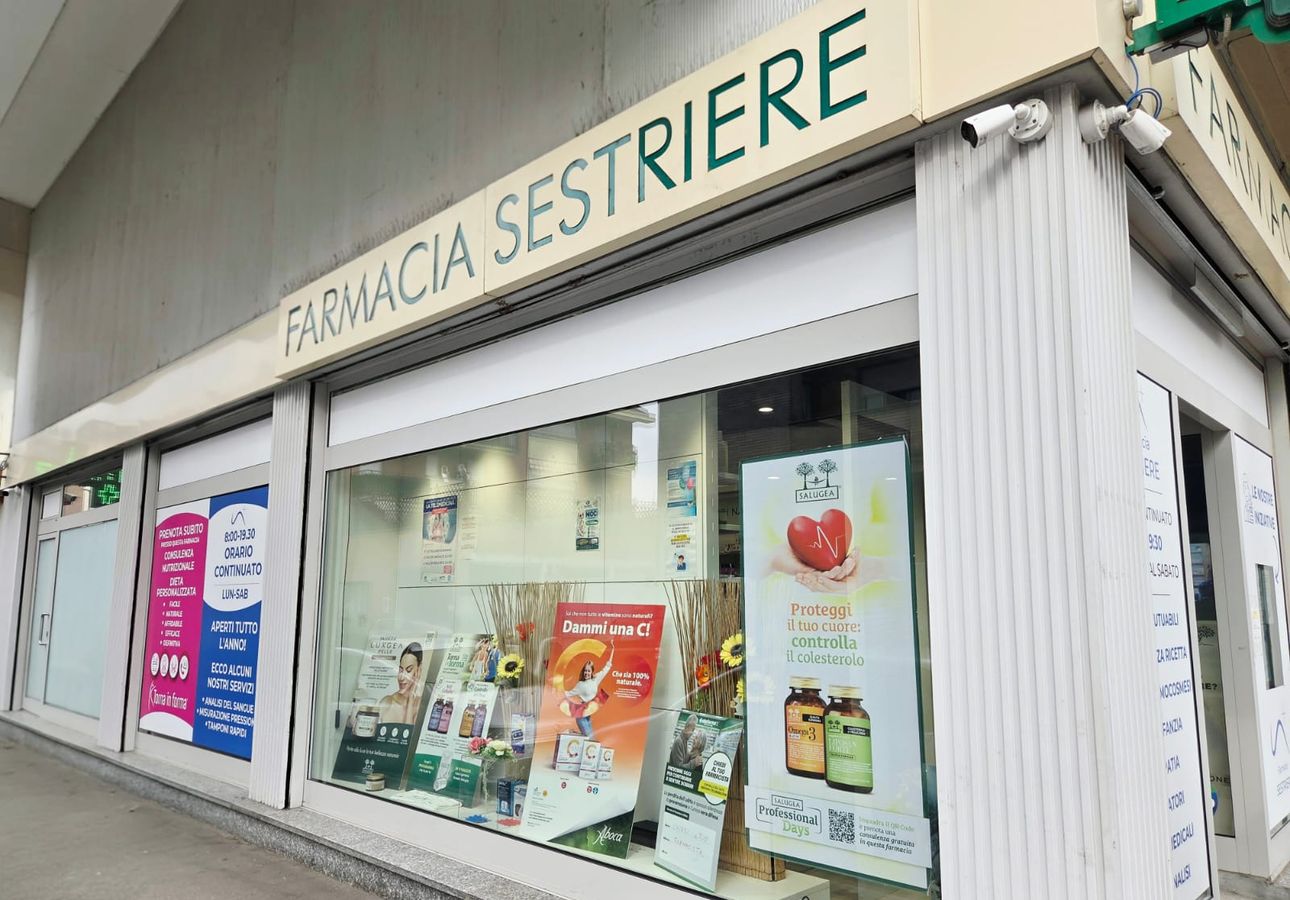 La facciata della Farmacia Sestriere con l'insegna verde, all'angolo con via Battisti